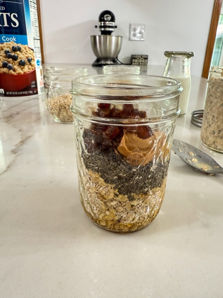 The oats, chia seeds, peanut butter, dates and maple syrup added to a small glass jar.