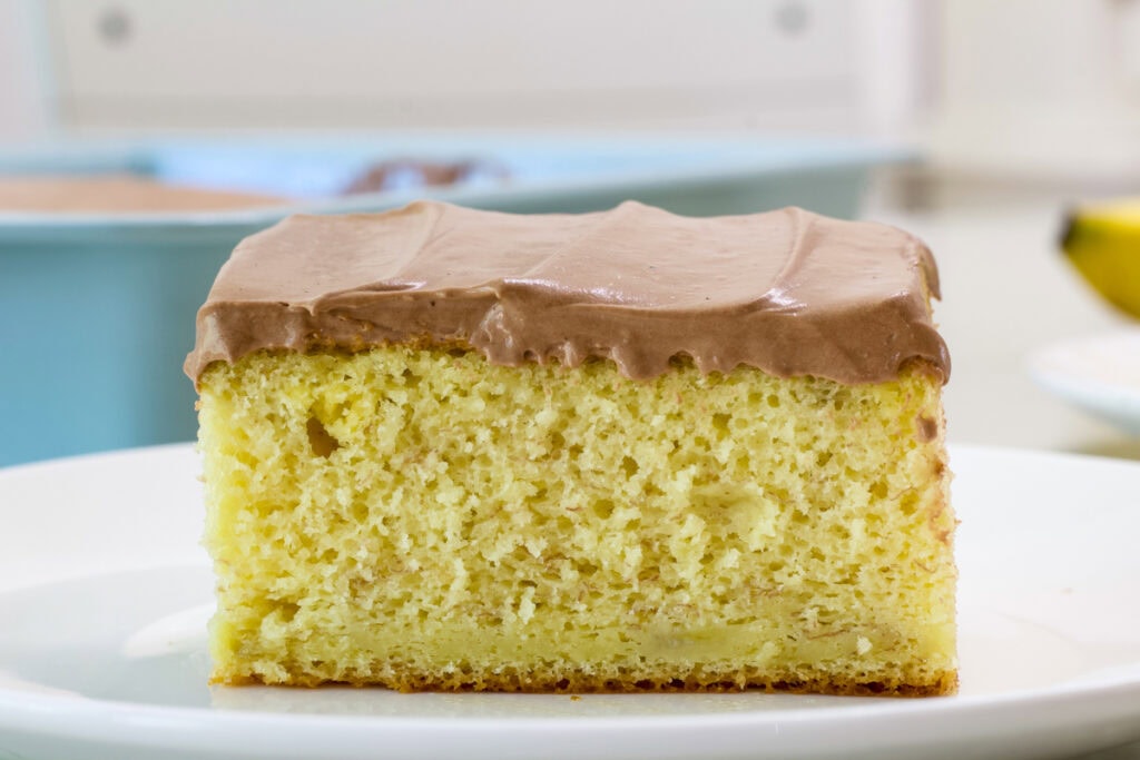 One piece of frosted banana cake so the crumb is visible.