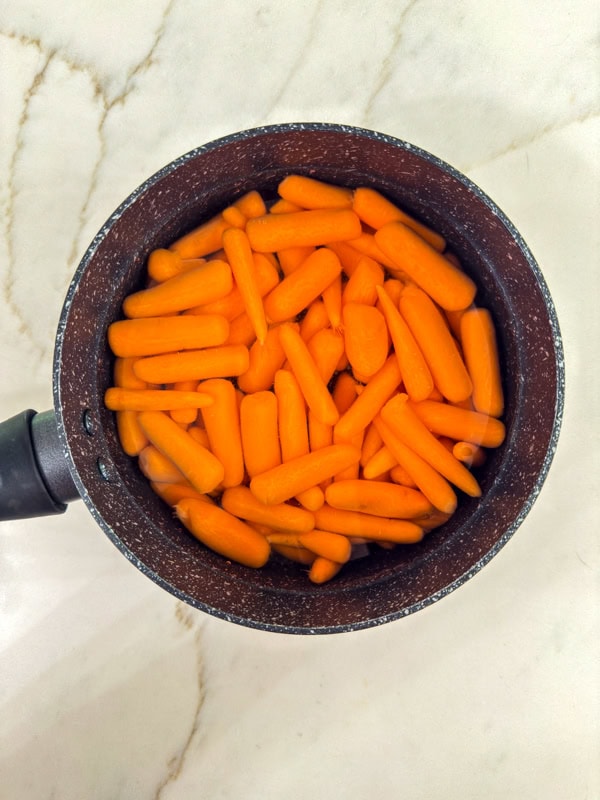 The carrots in a small saucepan covered with water ready to be cooked.