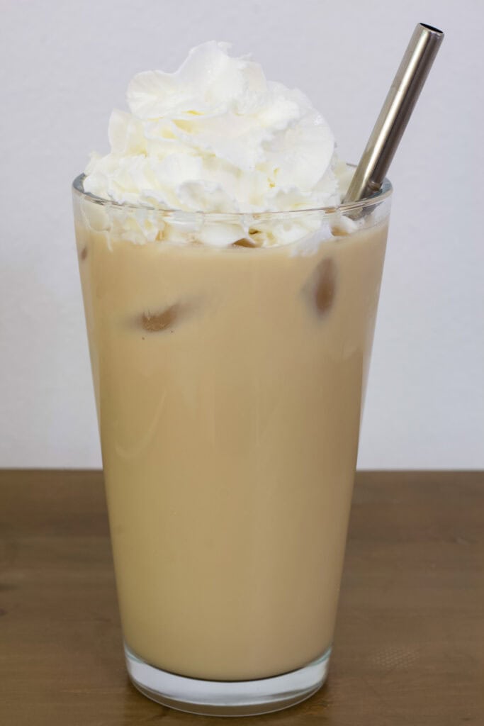 One Iced White Chocolate Mocha in a tall glass with a metal straw in it.