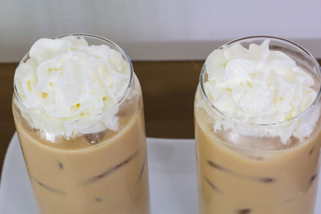 Overhead shot of two Iced White Chocolate Mochas topped with whipped cream.