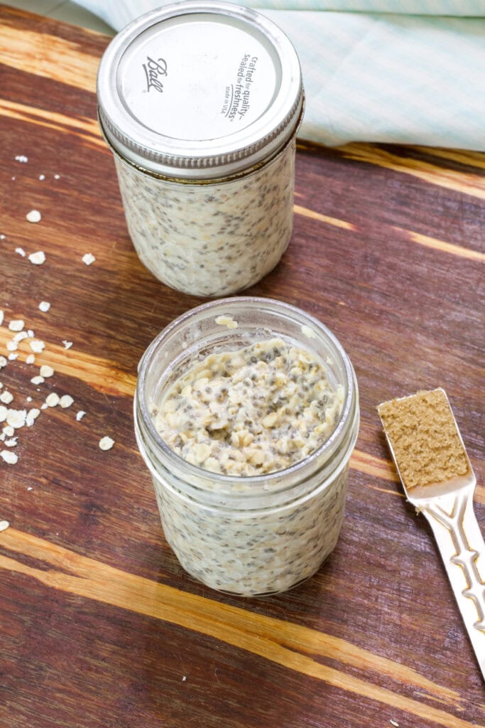 Overhead shot of two mason jars filled with Maple Brown Sugar Overnight Oats, one with a lid on and one without.