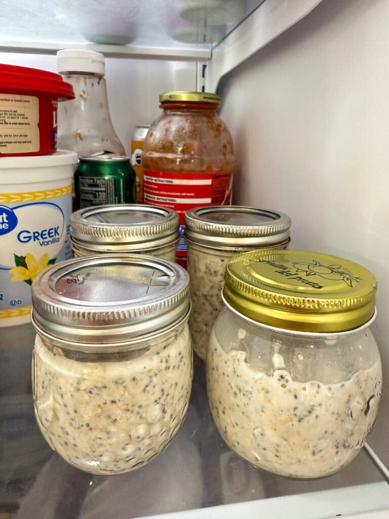 Four mason jars filled with Maple Brown Sugar Overnight Oats in the refrigerator.