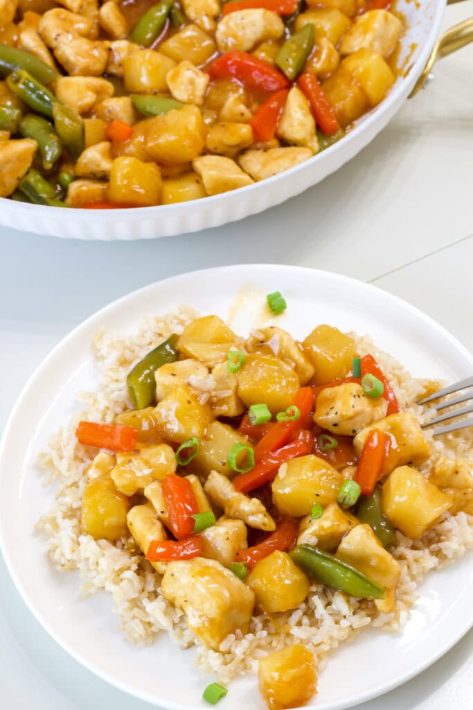 One serving of Orange Pineapple Chicken in the foreground and the pan with the remaining in the background.