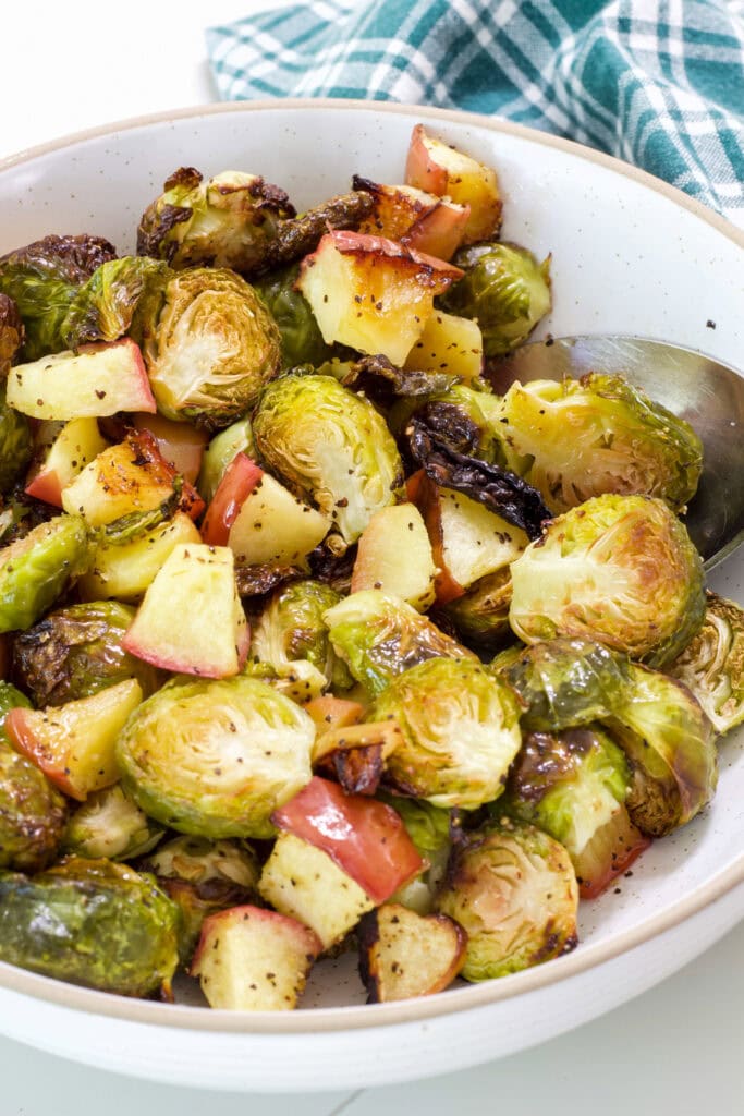 A serving bowl filled with the finished Oven Roasted Brussels Sprouts with Apples.
