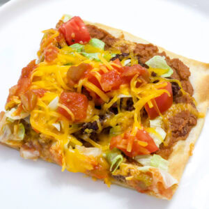 Overhead shot of one piece of taco pizza topped with lettuce, tomato, cheese and salsa on a white plate.