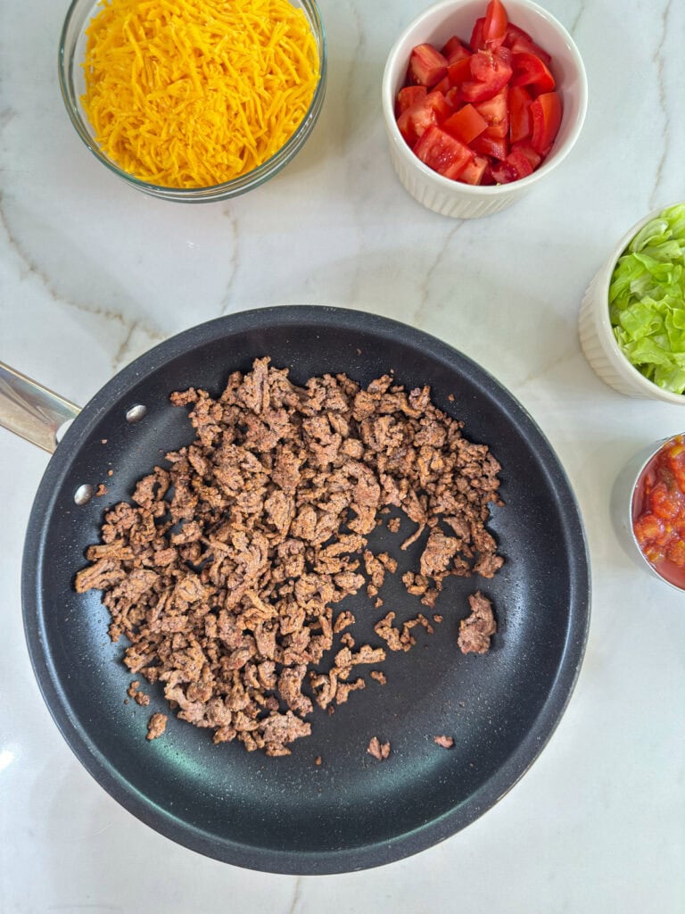 The cooked and seasoned ground beef in a large skillet.