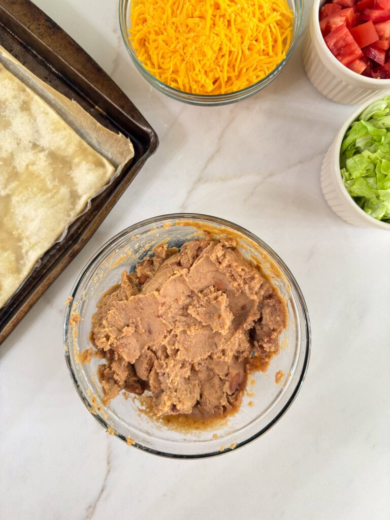The warmed refried beans in a glass microwave safe bowl.