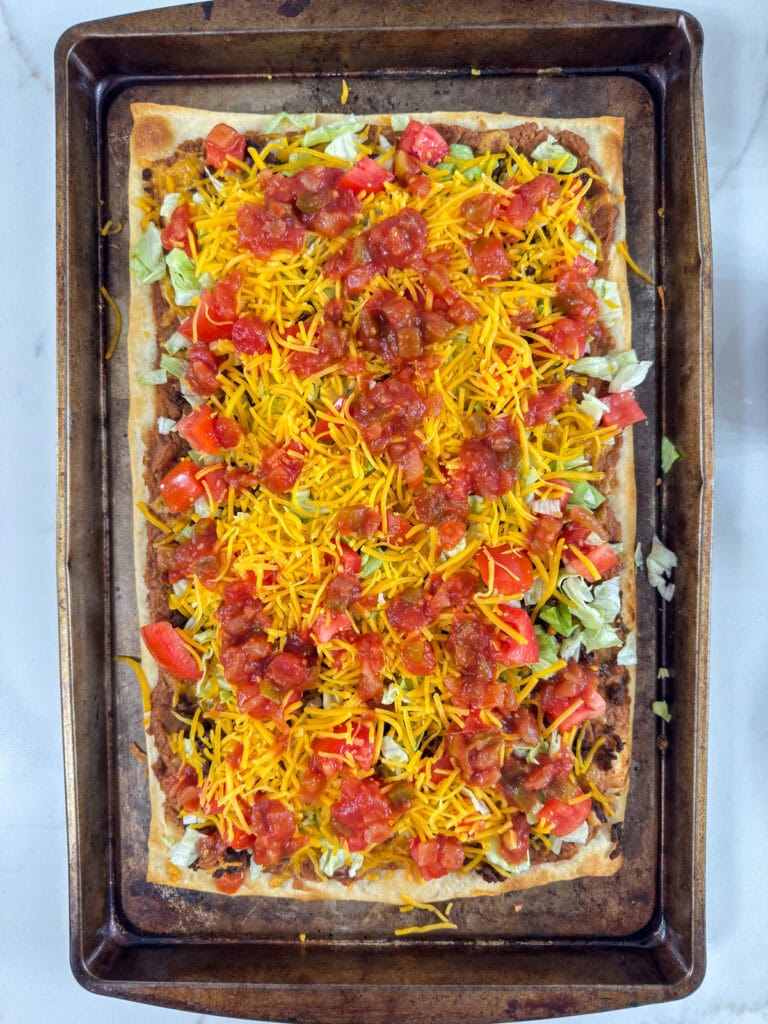 The finished pizza topped with the fresh vegetables, additional cheese and salsa.