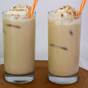 Feature image of two glasses of Iced Pumpkin Spice Latte on a wooden board.