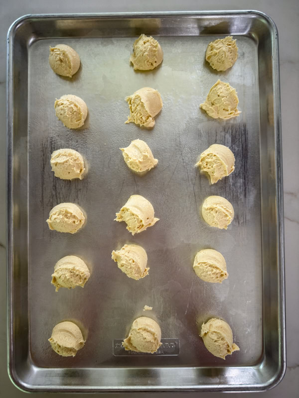 The cookie dough balls on the baking sheet before being flattened slightly.