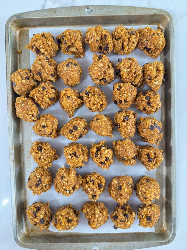 The pumpkin balls scooped out onto a parchment lined baking sheet before being rolled into balls.