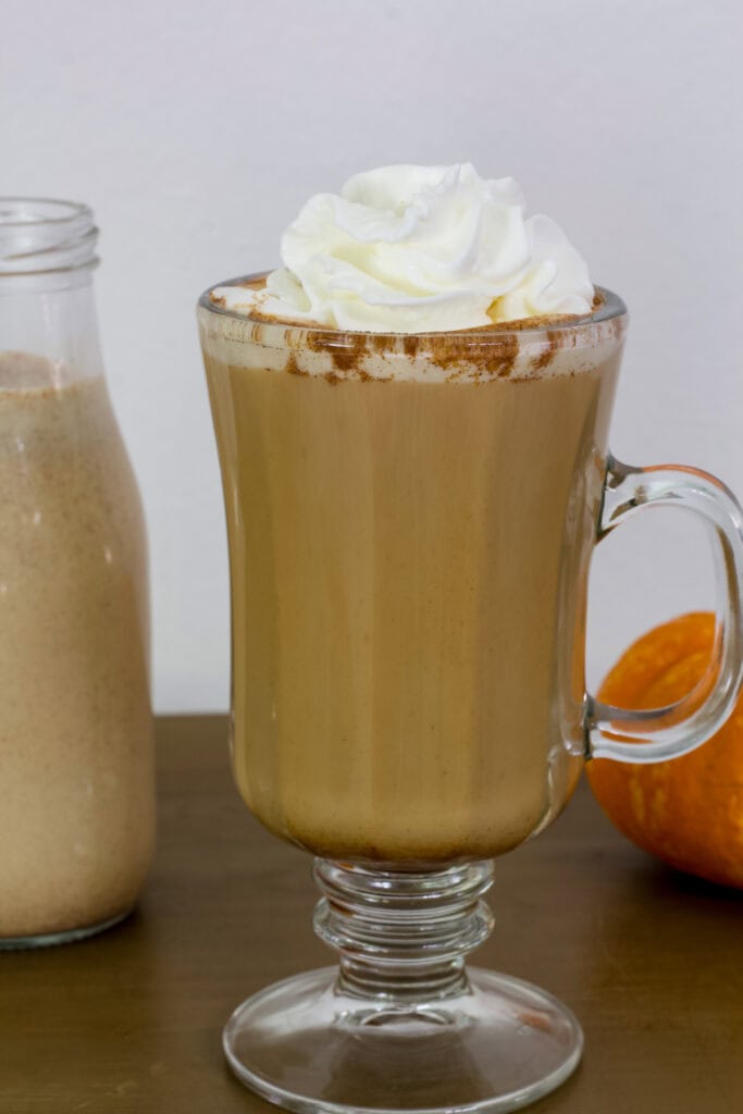 A cup of coffee with Pumpkin Spice Creamer in it topped with whipped cream.