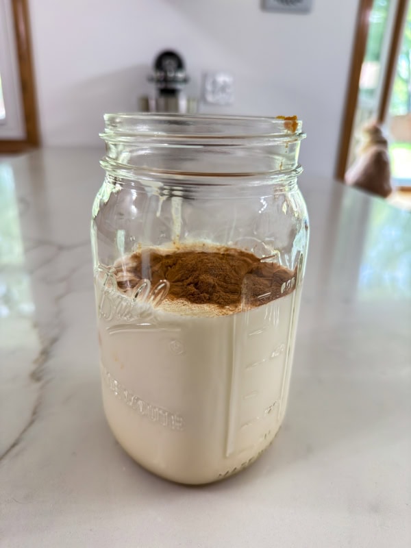 All of the ingredients added to a large mason jar before being whisked together.