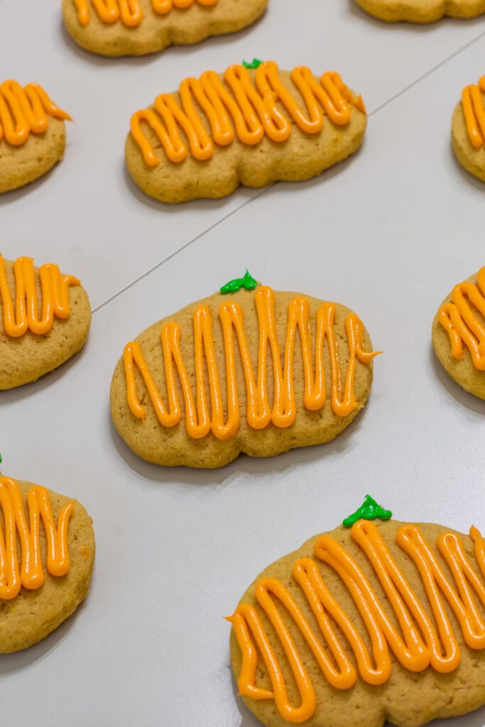 Several frosted Pumpkin Spice Cutout Cookies on a table.