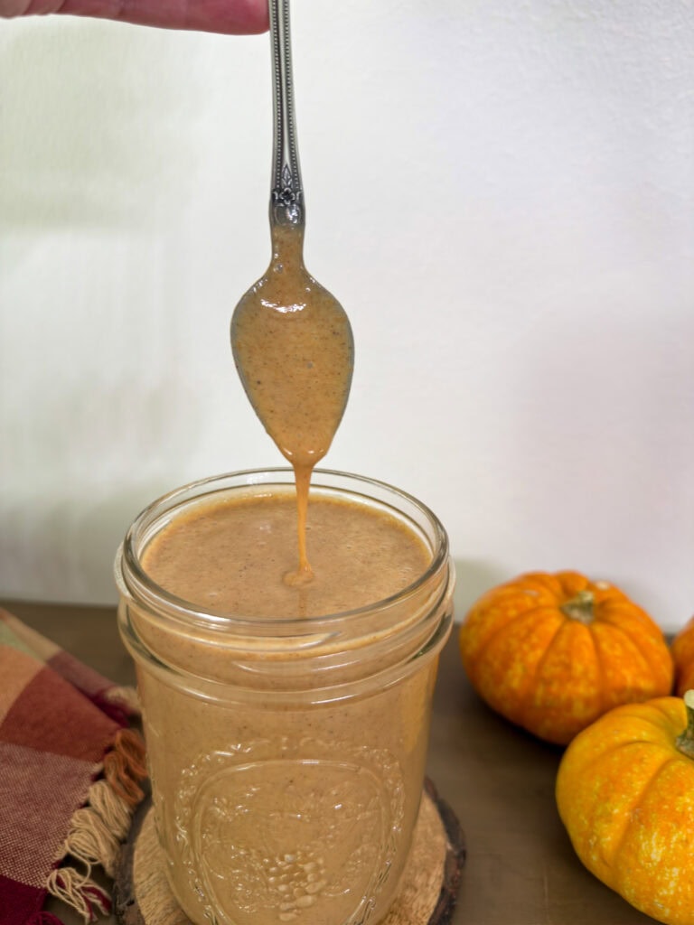 Some Starbucks Pumpkin Sauce dripping from a spoon into a mason jar.