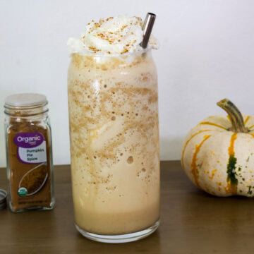 Feature image of the side view of one glass of Starbucks Pumpkin Spice Frappuccino.