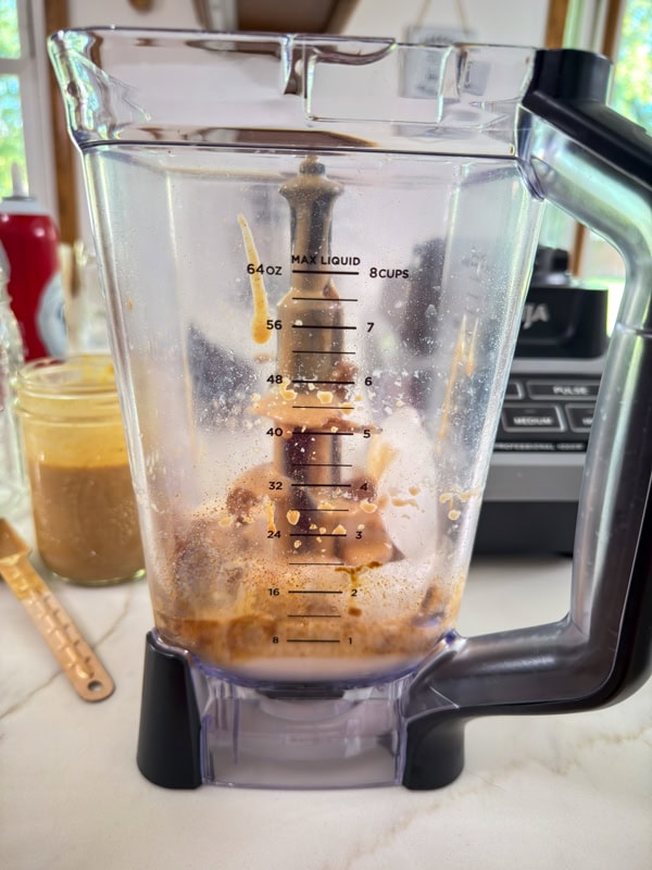 Everything needed to make the frappuccino in the pitcher of a blender before being blended.