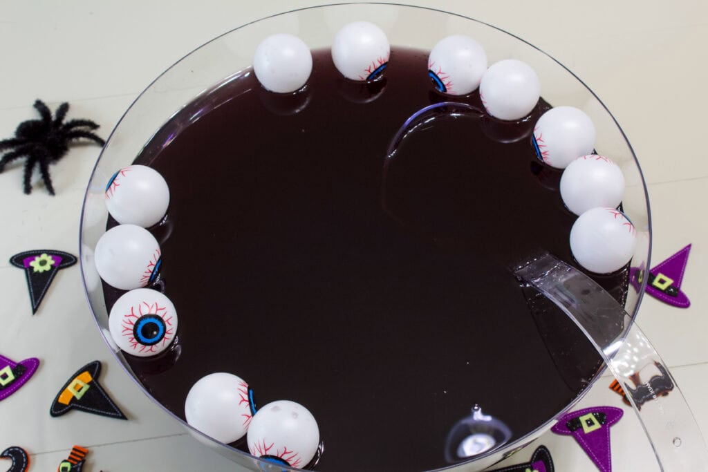Overhead shot of the entire punch bowl filled with Witches Brew Halloween Punch and some plastic eye balls.