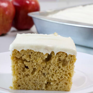 Very close up of the side on one piece of Apple Cider Cake with apples in the background.