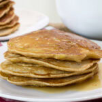 Close up side view of a stack of four Apple and Cinnamon Pancakes on a plate.