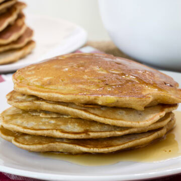 Close up side view of a stack of four Apple and Cinnamon Pancakes on a plate.