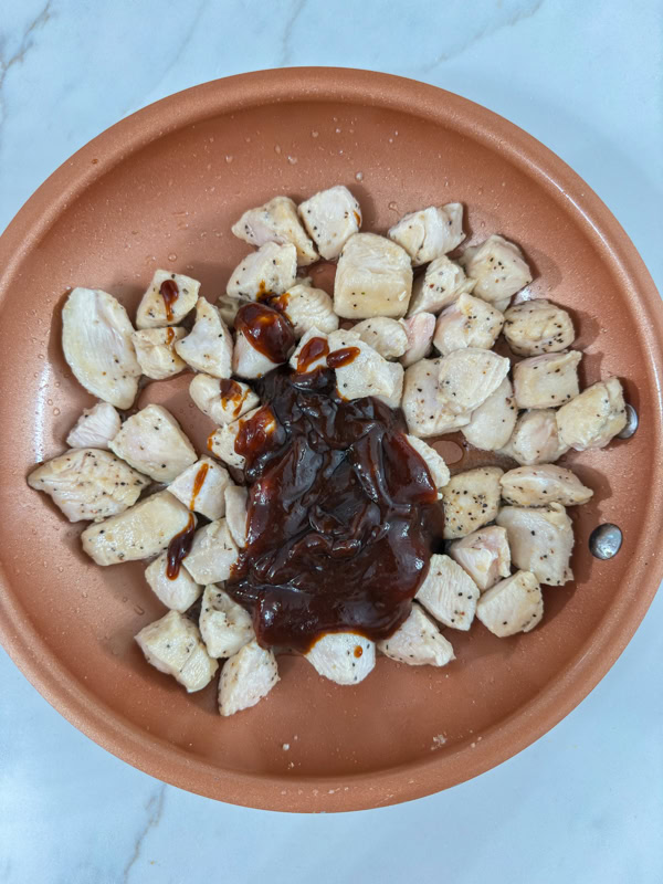 The barbecue sauce added to the skillet of cooked chicken.