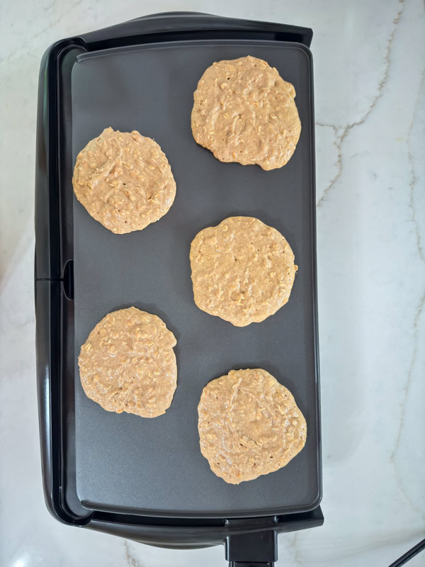 Five Healthy Sweet Potato Pancakes on a griddle before being turned over.