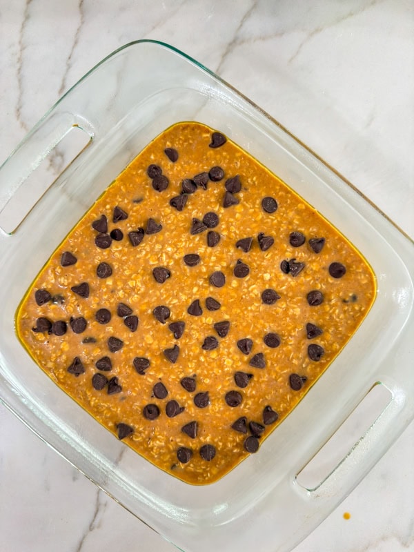 The unbaked batter in a baking dish topped with chocolate chips and ready to go into the oven.