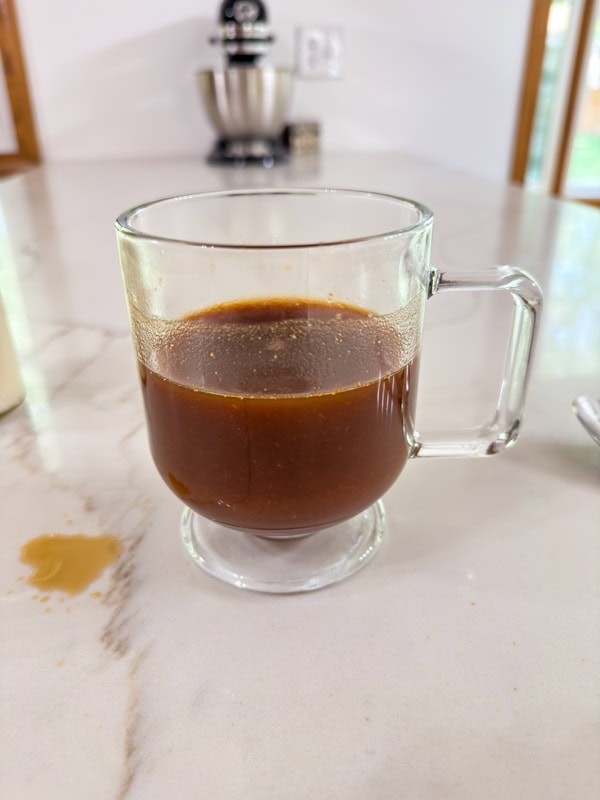 The hot coffee added to the pumpkin mixture in the coffee mug.