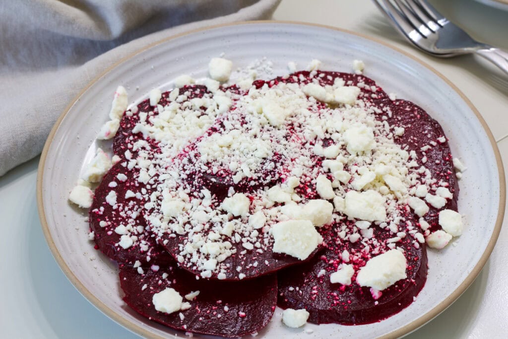Side view of one serving of beets and feta on a stoneware plate.
