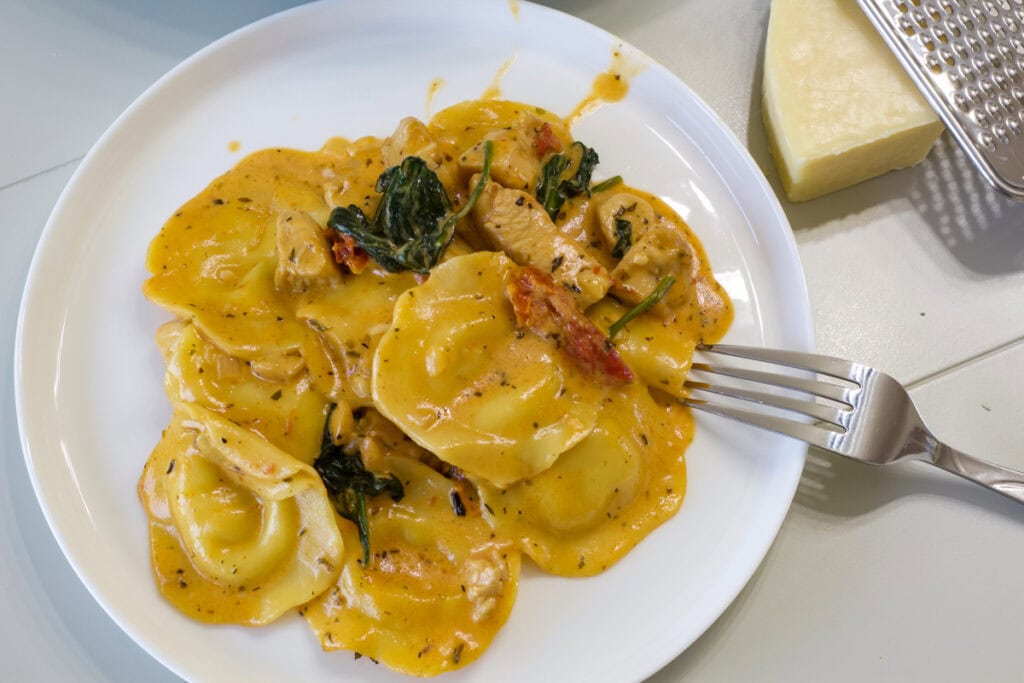 One serving of Tuscan Ravioli with Chicken on a white plate.