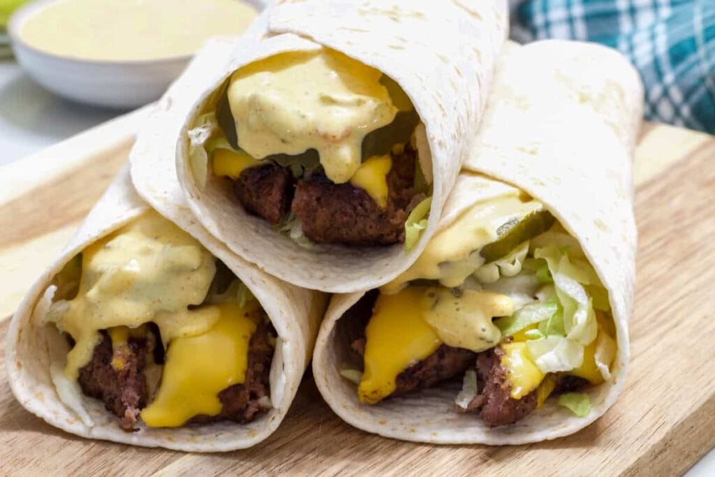Three Big Mac Wraps on a wooden cutting board so the end is visible.