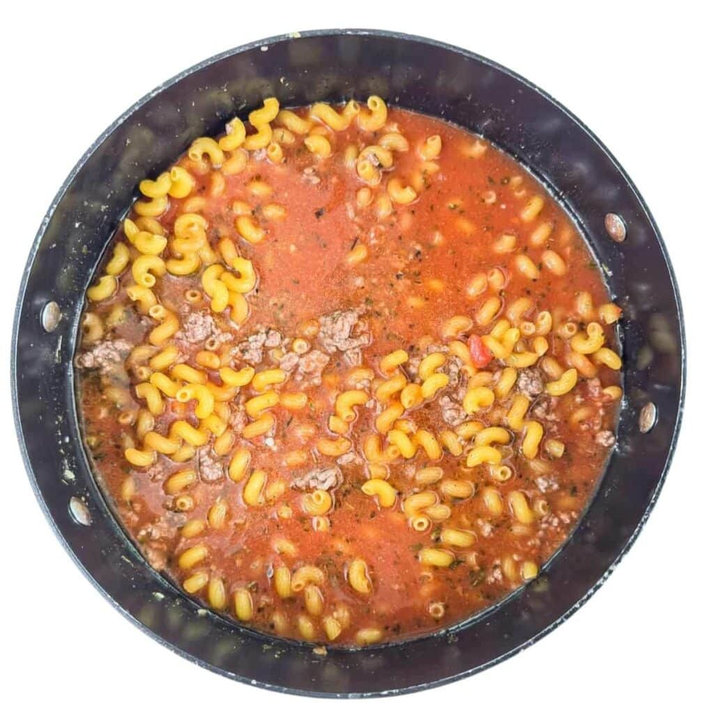 The sauce, water, and pasta added to the dutch oven.