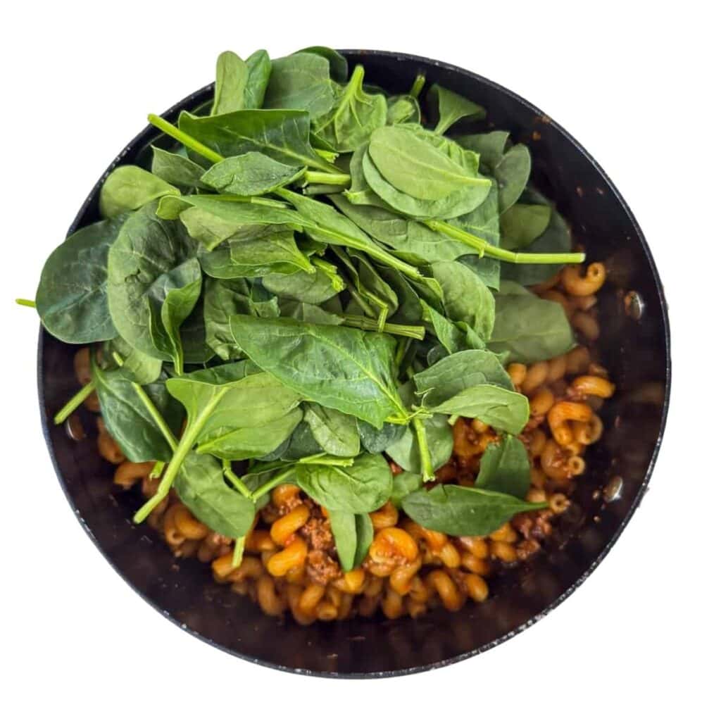The spinach added to the pot, before being mixed in.