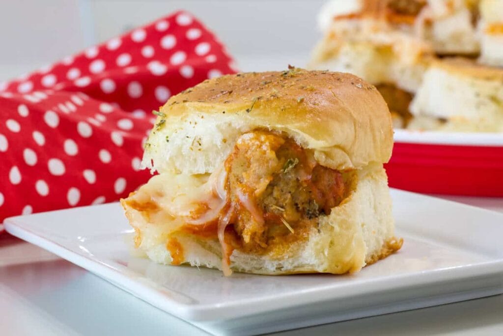 A close up side shot of one Meatball Slider on a Hawaiian Roll.