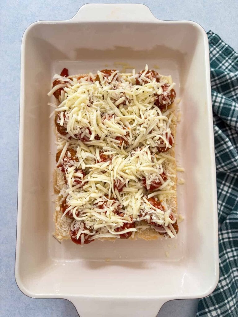 The bottom sliders with meatballs, sauce, and cheese on them.