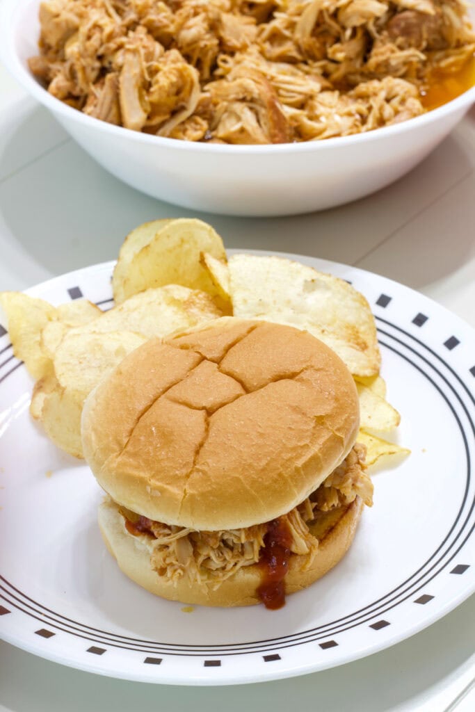 A serving of Slow Cooker Barbecue Chicken on a hamburger bun.