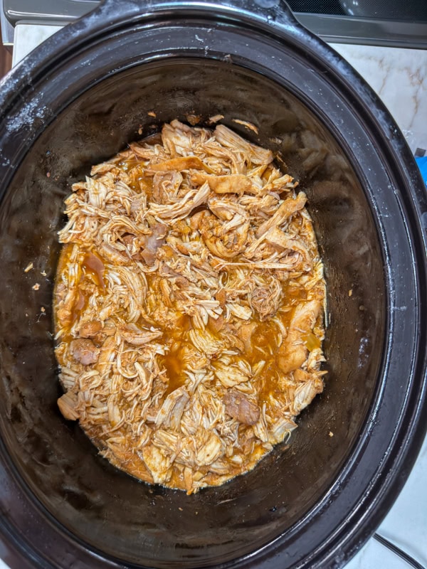 The cooked, shredded chicken in the crockpot.