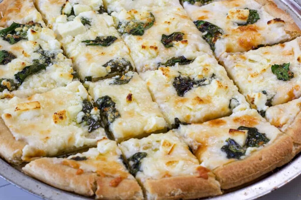 Half of a cut Spinach and Feta Pizza.