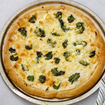 The whole finished Spinach and Feta Pizza on a silver pizza pan.