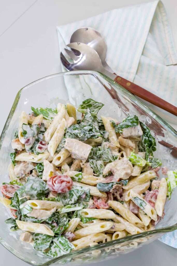 Overhead shot of the entire batch of Chicken BLT Pasta Salad in a glass salad bowl.