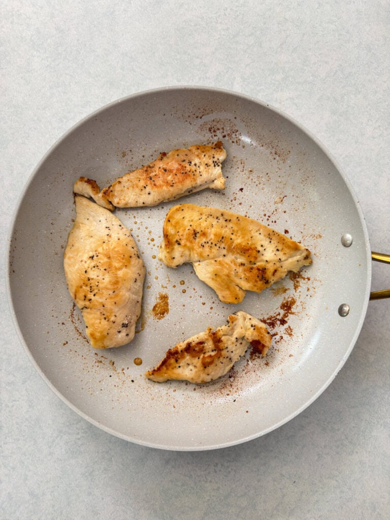 The cooked chicken breasts in a skillet.