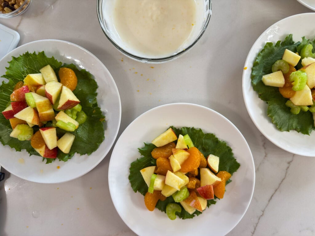 Overhead view of 3 serving plates with the salad on them, before adding the dressing.