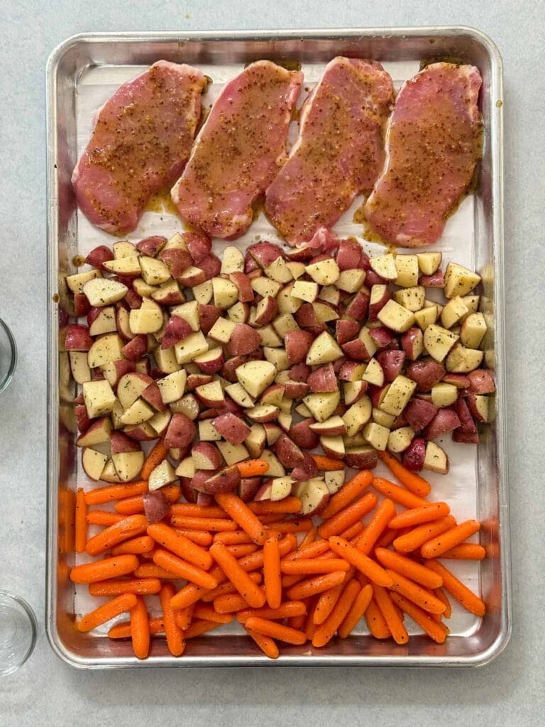 The pork chops have been added to the sheet pan and it's ready to go into the oven.