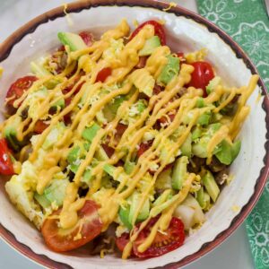 Overhead shot of one Breakfast Burrito Bowl with sausage, tomatoes, eggs, avocados and queso sauce.