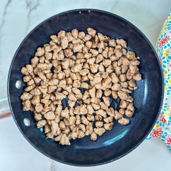 The sausage crumbles in a skillet after being browned.