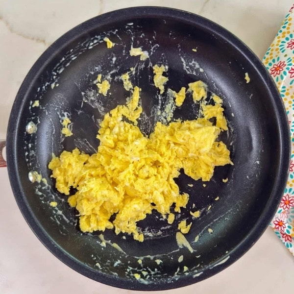 The scrambled eggs in a skillet.