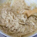 Very close up overhead of the Chicken Gravy in a skillet with a wooden spoon in it.