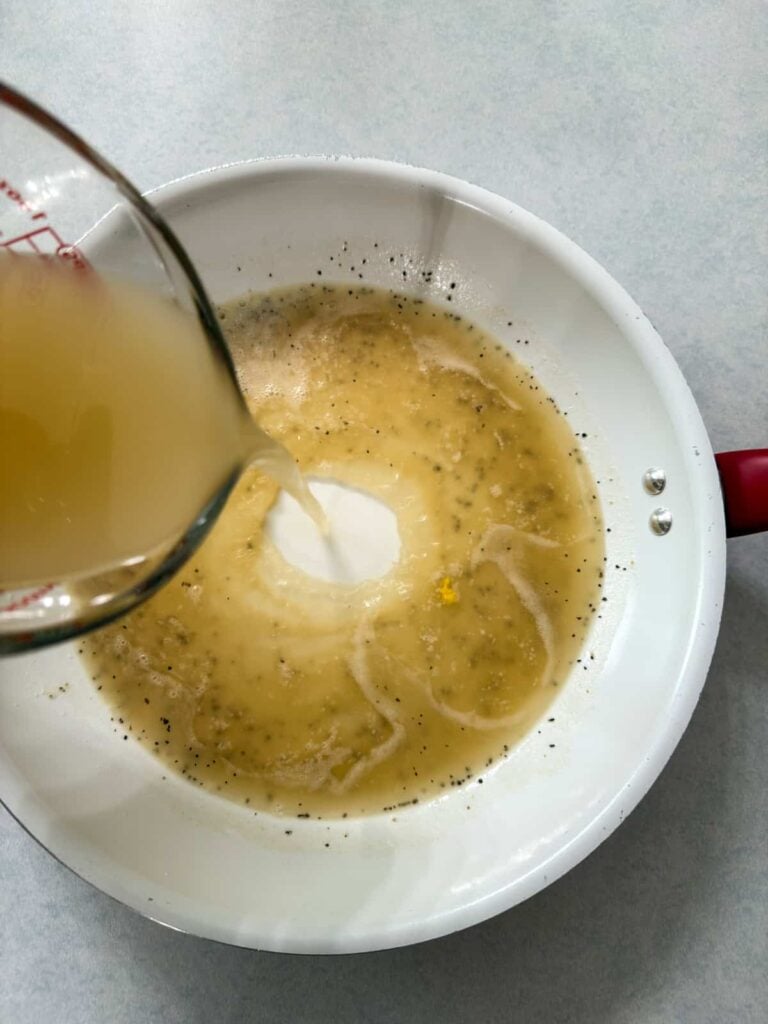 The chicken broth being poured into the roux.